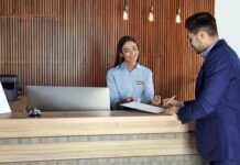 Recepcionista de hotel atiende a un cliente.